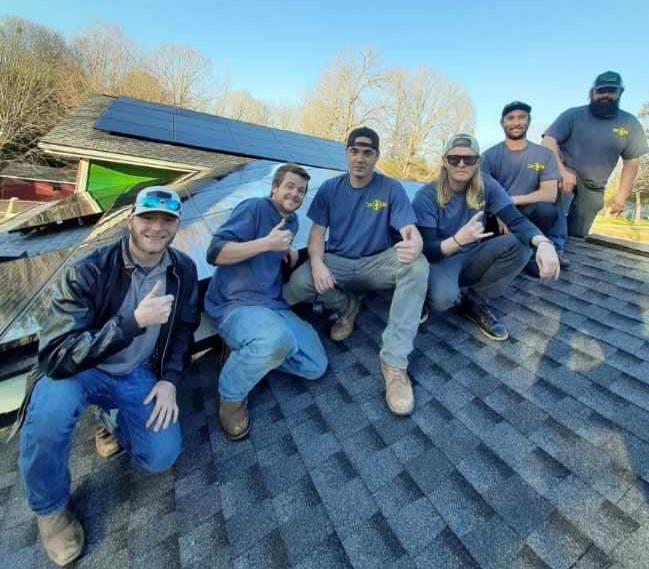 Zero Grid Power Solutions Team Members on a roof in front of a recent install.